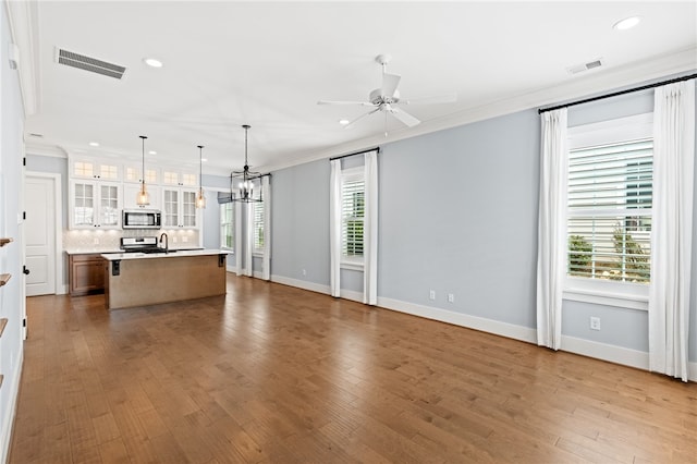 unfurnished living room featuring light hardwood / wood-style flooring, ceiling fan with notable chandelier, and crown molding