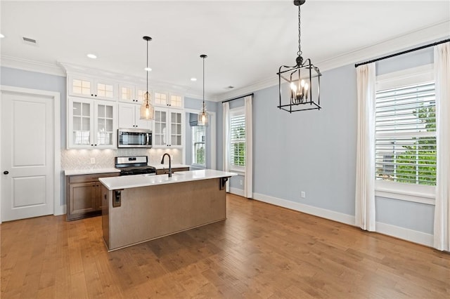 kitchen with backsplash, crown molding, appliances with stainless steel finishes, light countertops, and baseboards