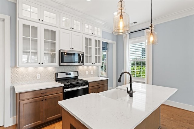 kitchen with hanging light fixtures, a sink, stainless steel appliances, white cabinetry, and tasteful backsplash
