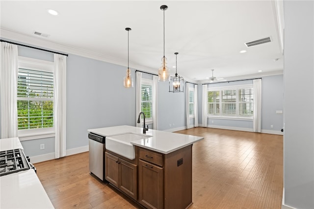 kitchen featuring stainless steel dishwasher, a center island with sink, plenty of natural light, and light wood-type flooring