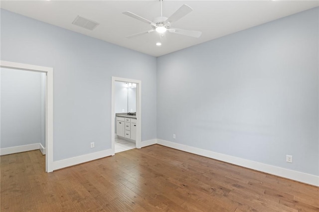 unfurnished bedroom featuring visible vents, baseboards, light wood finished floors, and ensuite bathroom