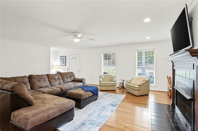 living room with ornamental molding, hardwood / wood-style flooring, a tile fireplace, and ceiling fan