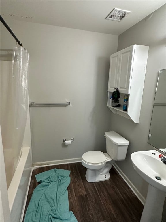 full bathroom with toilet, hardwood / wood-style flooring, shower / bath combo with shower curtain, and sink