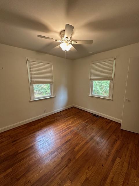 unfurnished room featuring dark wood-type flooring, ceiling fan, and plenty of natural light