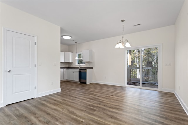 unfurnished living room featuring baseboards, wood finished floors, visible vents, and an inviting chandelier