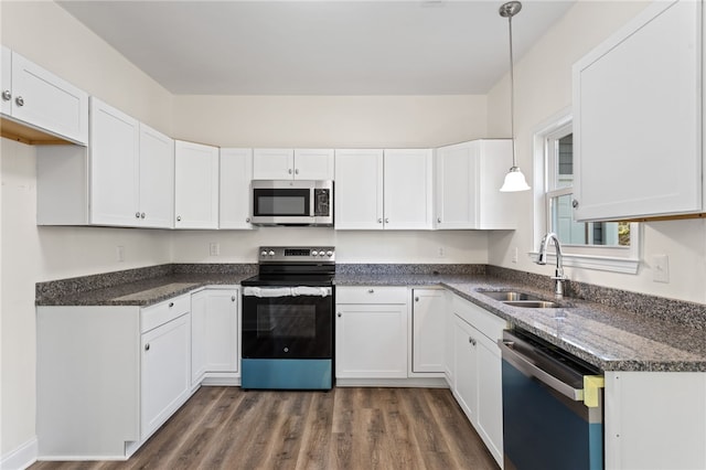 kitchen with a sink, white cabinets, appliances with stainless steel finishes, dark wood finished floors, and pendant lighting