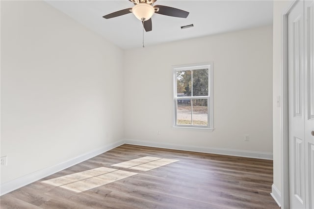 unfurnished room with a ceiling fan, visible vents, baseboards, and wood finished floors