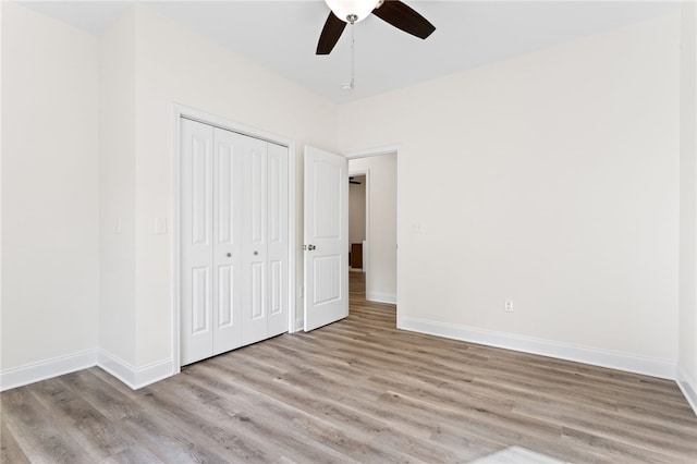 unfurnished bedroom with a closet, wood finished floors, a ceiling fan, and baseboards