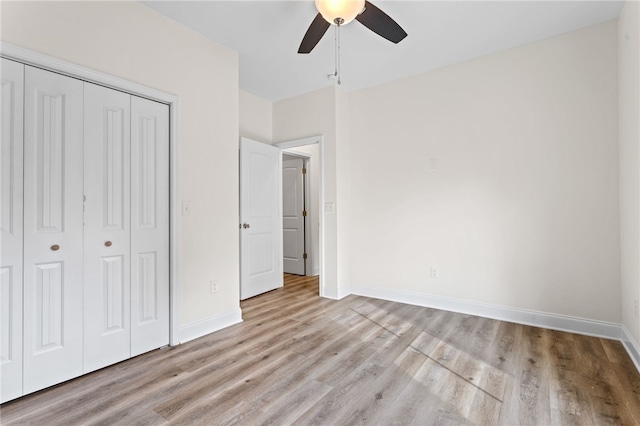 unfurnished bedroom featuring light wood-style floors, ceiling fan, baseboards, and a closet