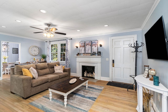 living room featuring ornamental molding, a brick fireplace, light hardwood / wood-style floors, and ceiling fan