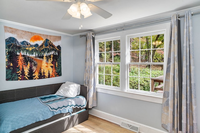 bedroom with multiple windows, ornamental molding, light wood-type flooring, and ceiling fan