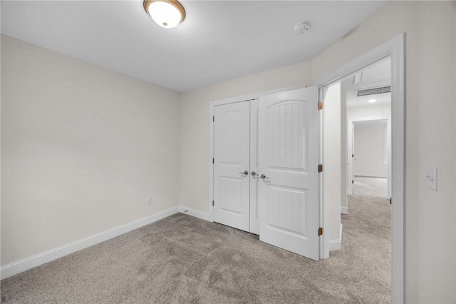 unfurnished bedroom featuring a closet and light colored carpet