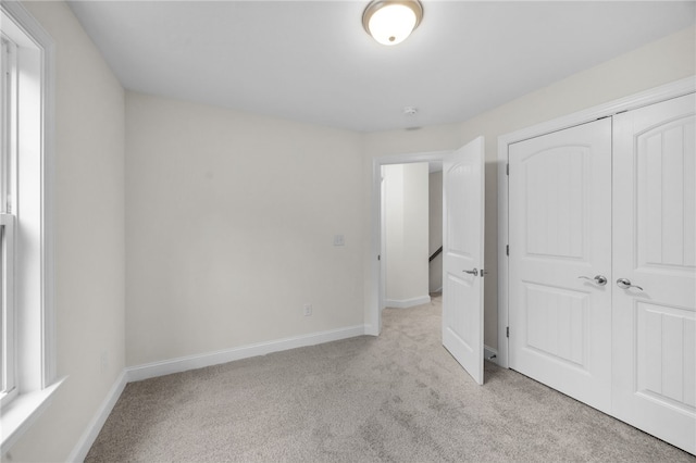 unfurnished bedroom with light carpet and a closet