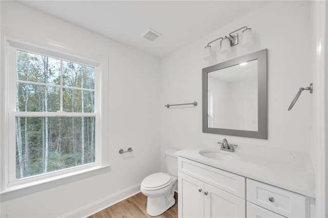 bathroom featuring vanity, toilet, plenty of natural light, and hardwood / wood-style floors