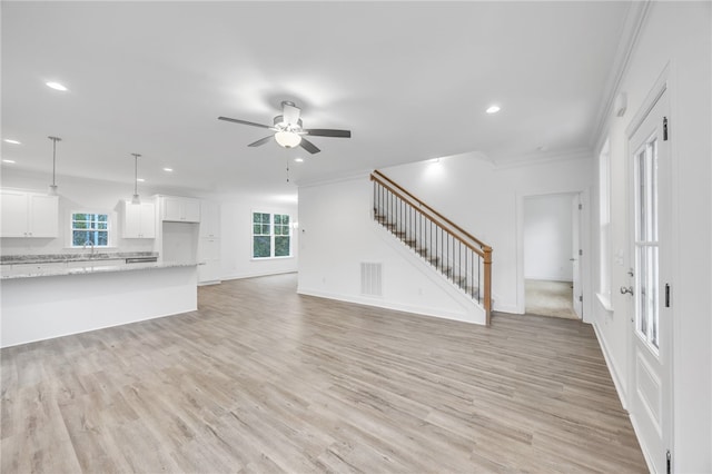 unfurnished living room with light wood-type flooring, ornamental molding, plenty of natural light, and ceiling fan