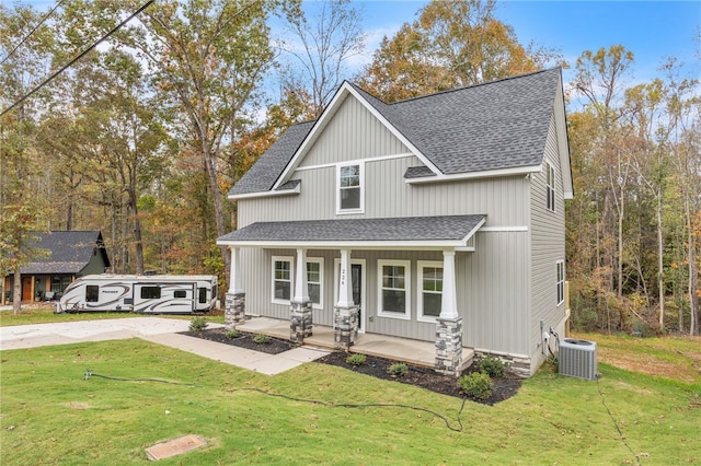 view of front of home with covered porch, a front yard, and cooling unit