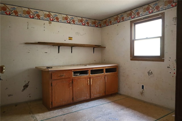 interior space with open shelves, brown cabinets, and light countertops