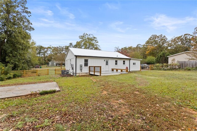 back of house featuring metal roof, a lawn, and fence