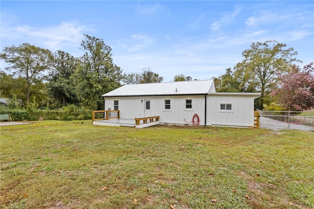 back of property featuring fence, a wooden deck, a lawn, board and batten siding, and metal roof