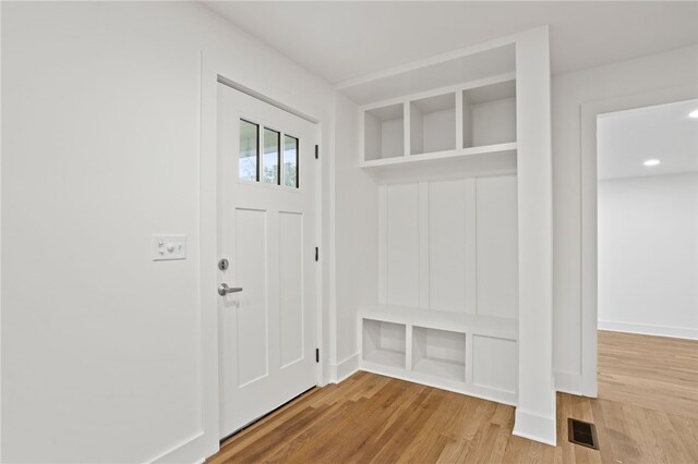 mudroom featuring visible vents, baseboards, and wood finished floors