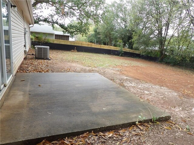 view of patio featuring cooling unit, fence, and view of scattered trees