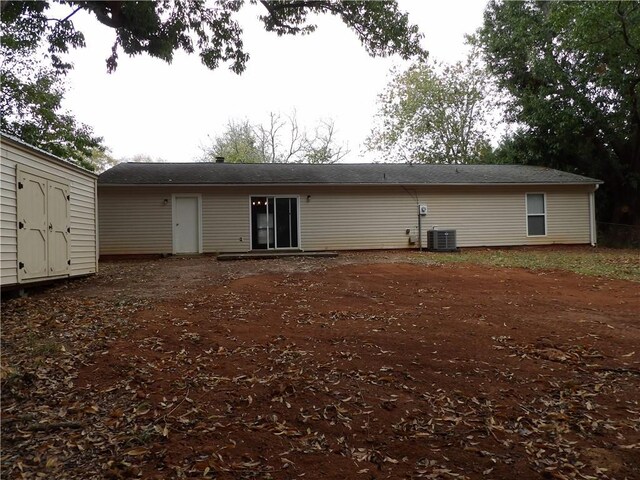 back of house featuring central AC unit and a storage unit