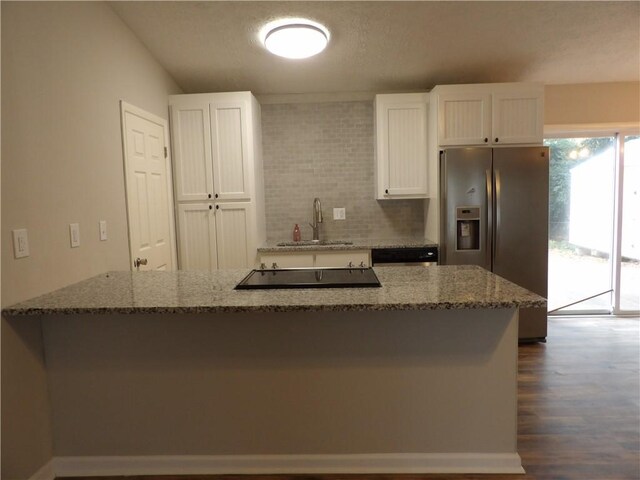 kitchen with stainless steel refrigerator with ice dispenser, a sink, light stone counters, and white cabinetry