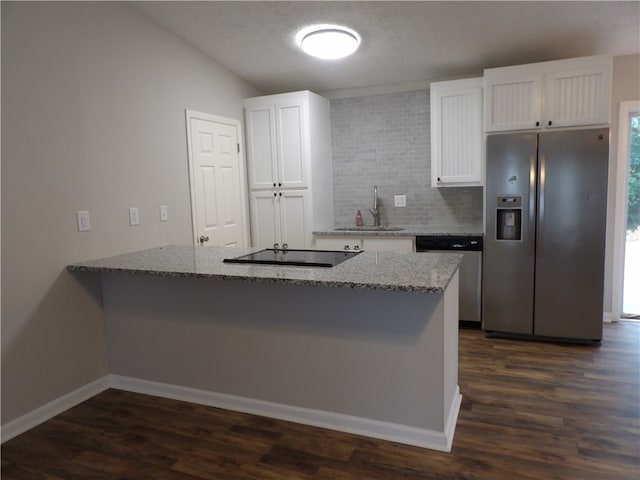 kitchen featuring white cabinetry, kitchen peninsula, light stone counters, appliances with stainless steel finishes, and dark hardwood / wood-style flooring