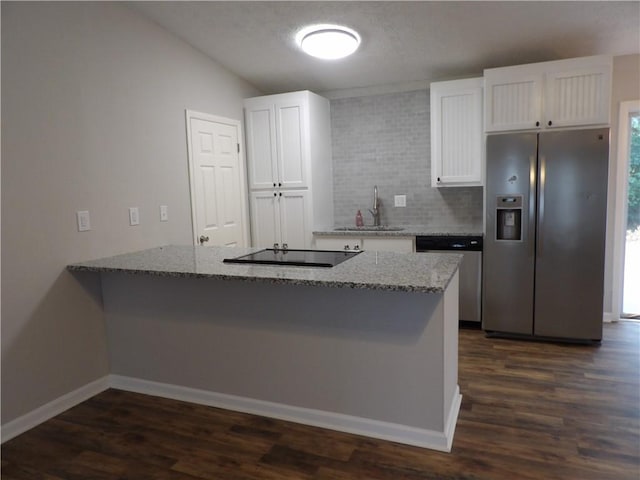 kitchen featuring appliances with stainless steel finishes, light stone counters, white cabinets, and dark wood-style flooring