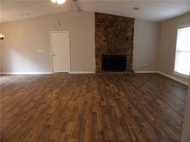 unfurnished living room with lofted ceiling with beams, a stone fireplace, a textured ceiling, dark hardwood / wood-style flooring, and ceiling fan