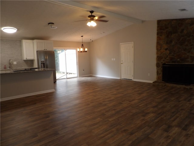 unfurnished living room with sink, ceiling fan with notable chandelier, a fireplace, vaulted ceiling with beams, and dark wood-type flooring