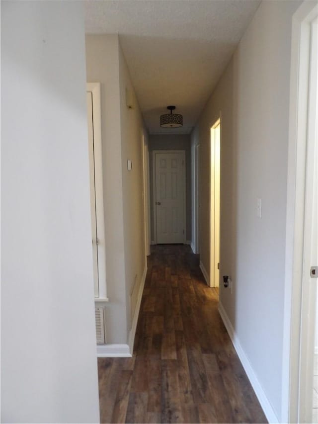 hall featuring dark wood-style flooring and baseboards