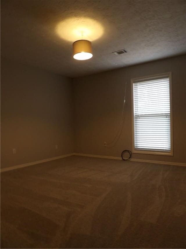 carpeted empty room with baseboards and a textured ceiling