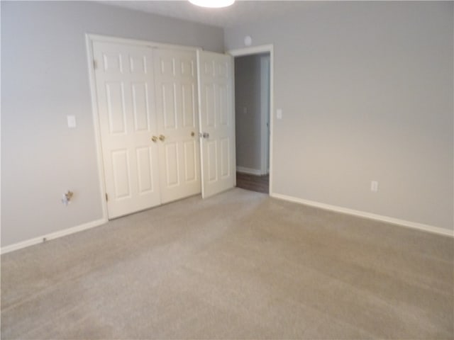 unfurnished bedroom featuring light colored carpet and a closet