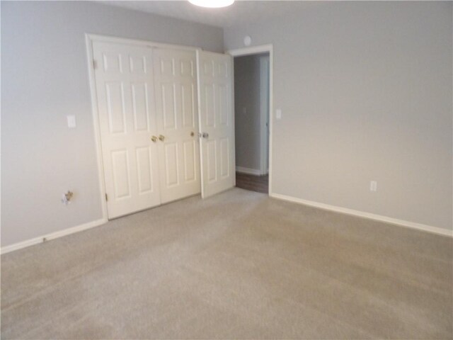 unfurnished bedroom with carpet floors, baseboards, and a closet