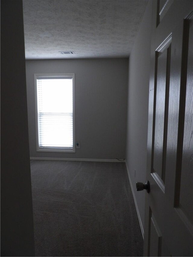 carpeted spare room with baseboards and a textured ceiling
