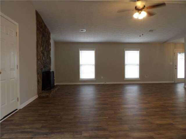 unfurnished living room featuring a ceiling fan, dark wood-style floors, baseboards, and a wood stove