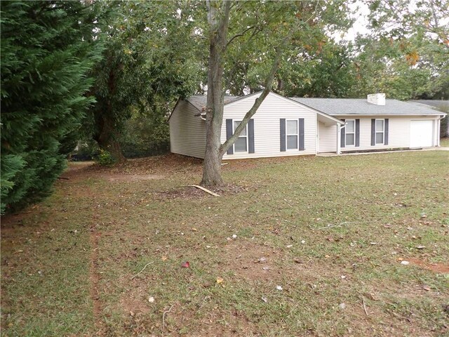 view of front facade featuring a front lawn, a garage, and a chimney