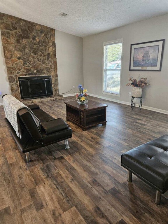 living area with wood finished floors, a textured ceiling, a fireplace, and baseboards