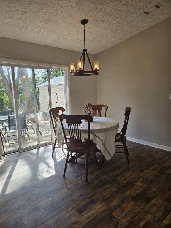 dining room featuring a chandelier, dark wood-style floors, a textured ceiling, and baseboards