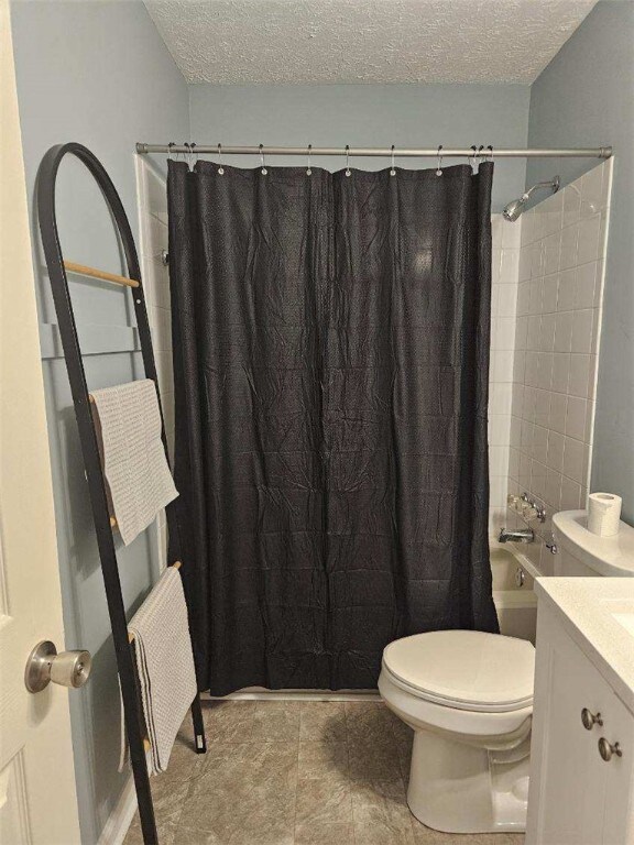bathroom featuring a textured ceiling, toilet, shower / tub combo, and vanity