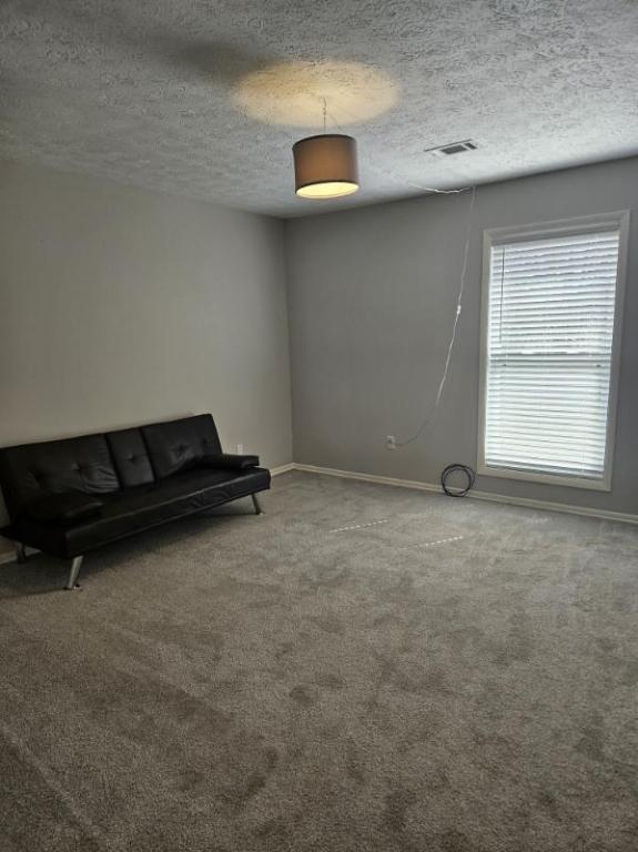 unfurnished room with carpet, baseboards, and a textured ceiling