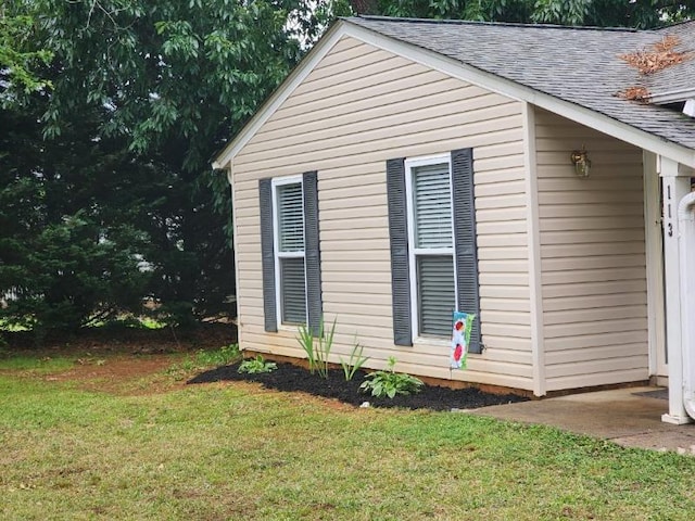 view of side of property featuring a shingled roof and a lawn