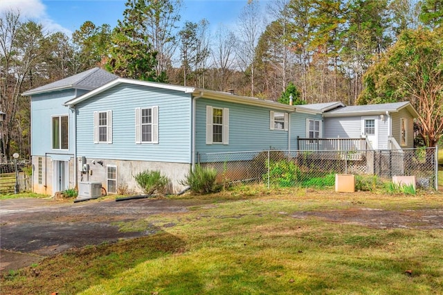 rear view of house with fence, a lawn, and central AC