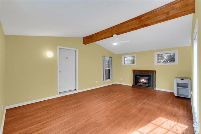 unfurnished living room featuring vaulted ceiling with beams, light wood-style floors, baseboards, and a glass covered fireplace