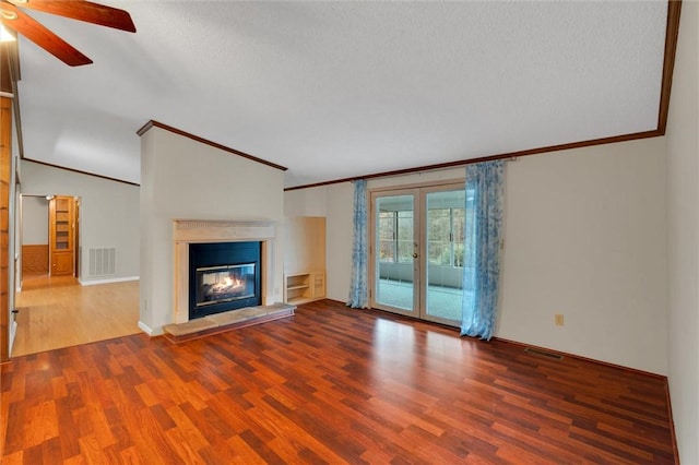 unfurnished living room with wood finished floors, visible vents, french doors, a glass covered fireplace, and crown molding