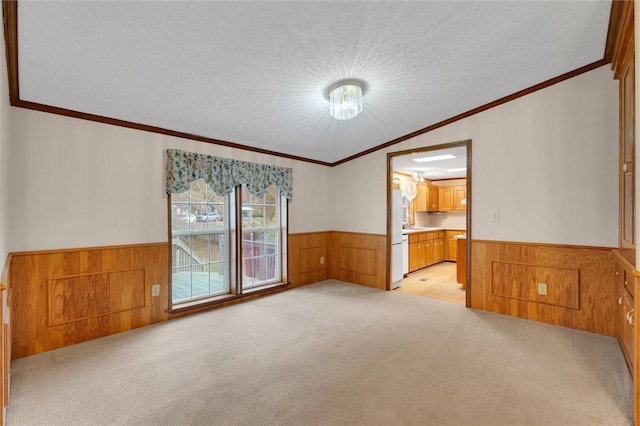 unfurnished room featuring a textured ceiling, light colored carpet, vaulted ceiling, and ornamental molding