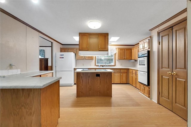 kitchen featuring white appliances, crown molding, a textured ceiling, light hardwood / wood-style floors, and kitchen peninsula