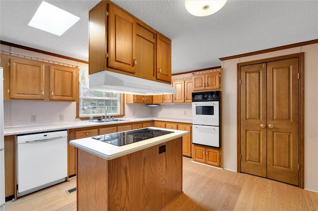 kitchen with a center island, sink, light hardwood / wood-style floors, white appliances, and ornamental molding