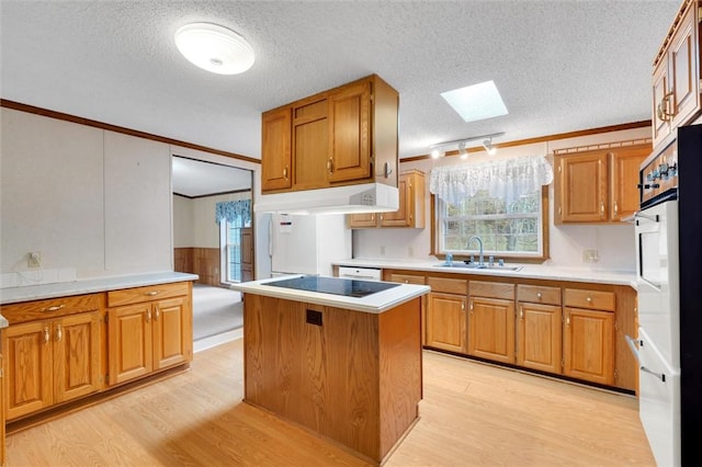 kitchen with light wood-type flooring, a textured ceiling, a center island, and sink